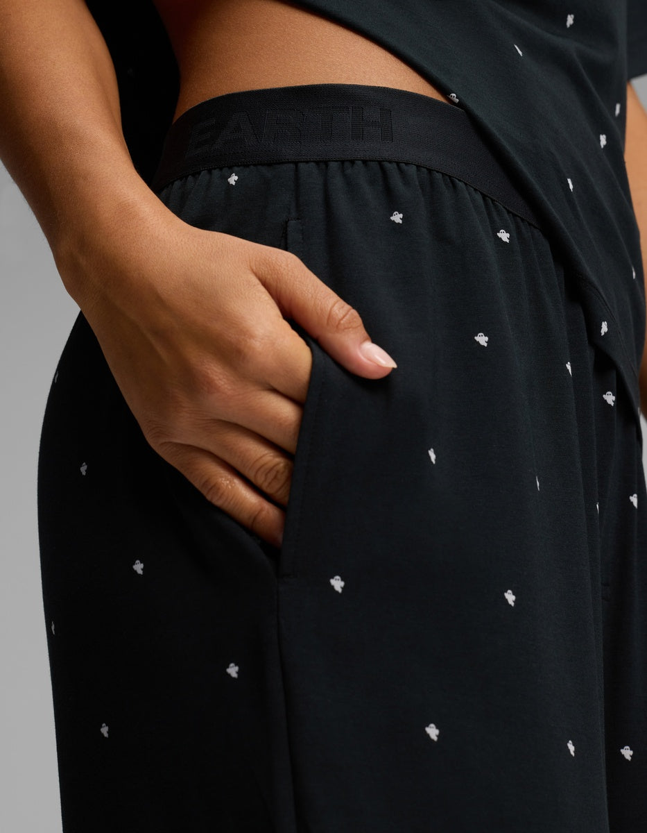Close-up of a person’s hand in the pocket of Cozy Earth Women’s First Layer Pajama Pant, featuring a black fabric with small white dot patterns. The waistband displays subtle branding, and the person pairs it with a matching black top.