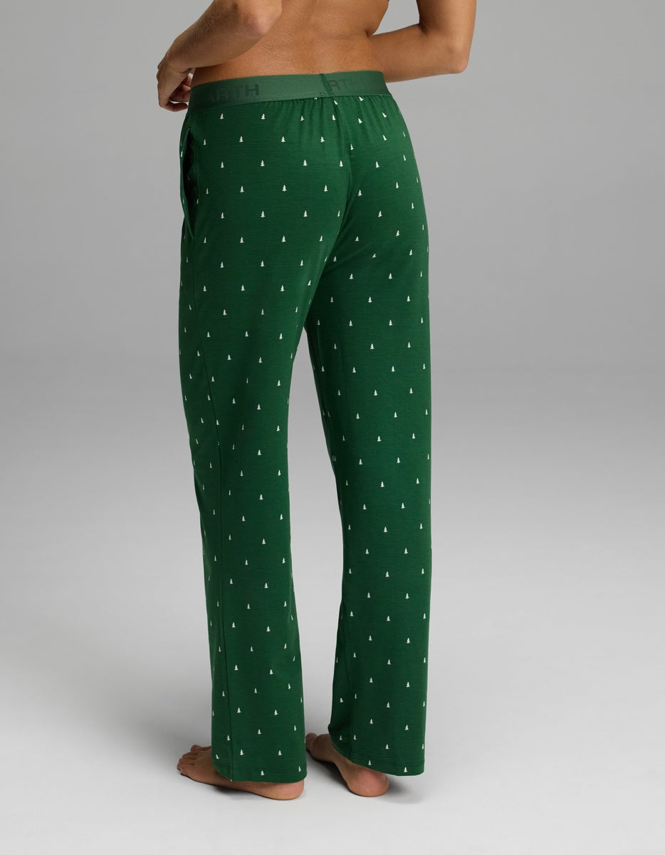 A person from the back wearing Cozy Earth Women’s First Layer Pajama Pant, which are green with a small white tree pattern and an elastic waistband.