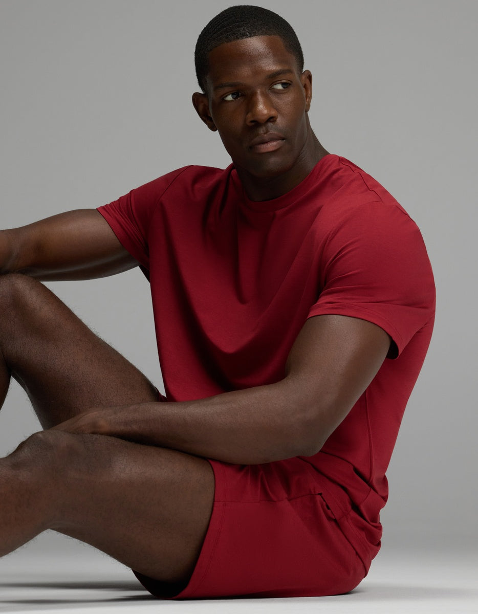 A man sitting while wearing a matching dark red crewneck t-shirt and Men’s First Layer Pajama Short.
