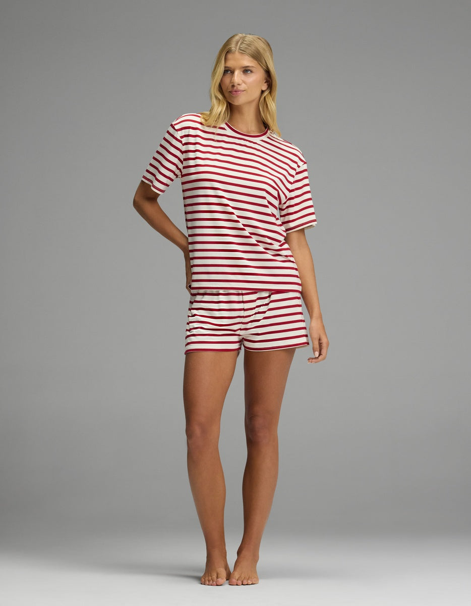 A woman wearing a Cozy Earth Women’s First Layer Pajama Short Sleeve Tee & Boxer Short Set featuring red and white horizontal stripes.