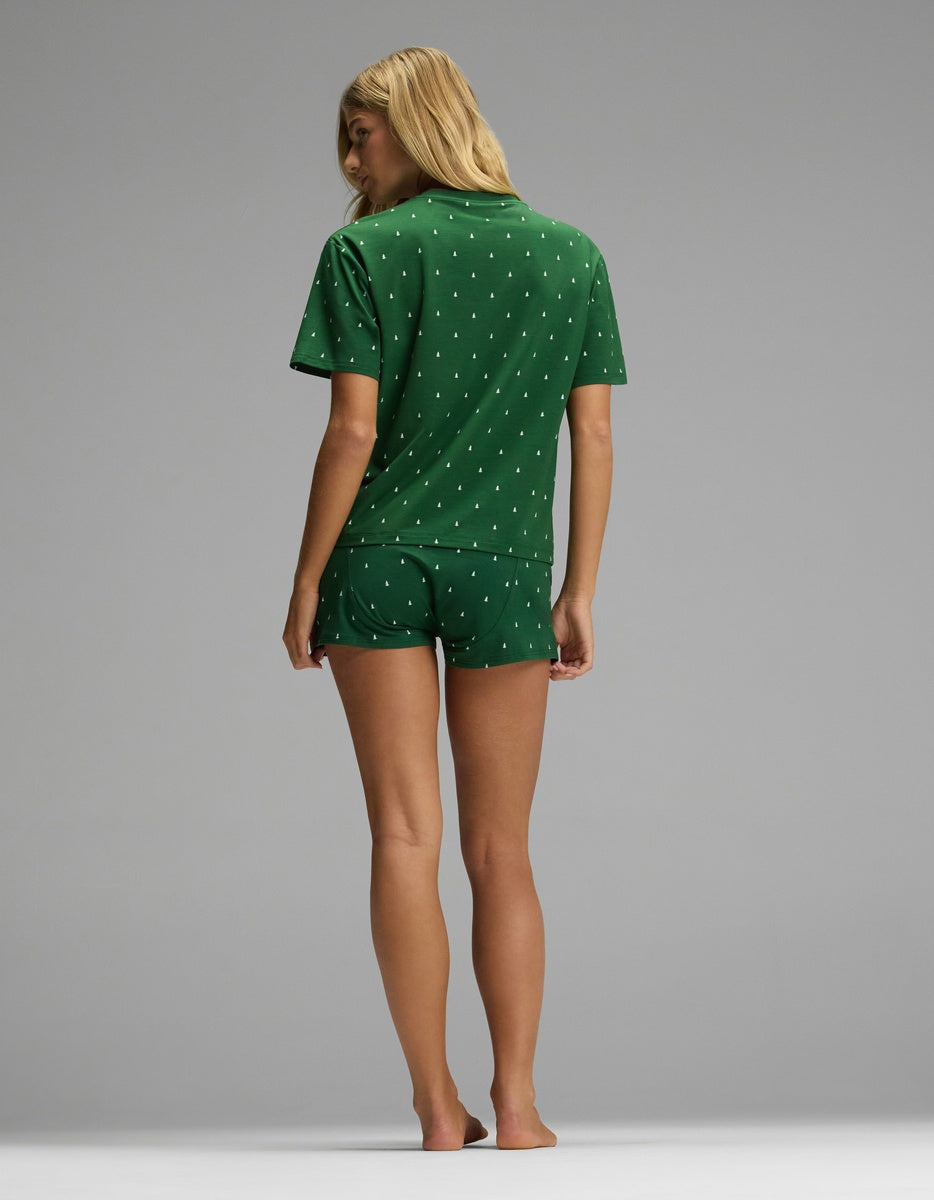 Back view of a person wearing a green Cozy Earth Women’s First Layer Pajama Short Sleeve Tee & Boxer Short Set featuring a small white tree pattern.