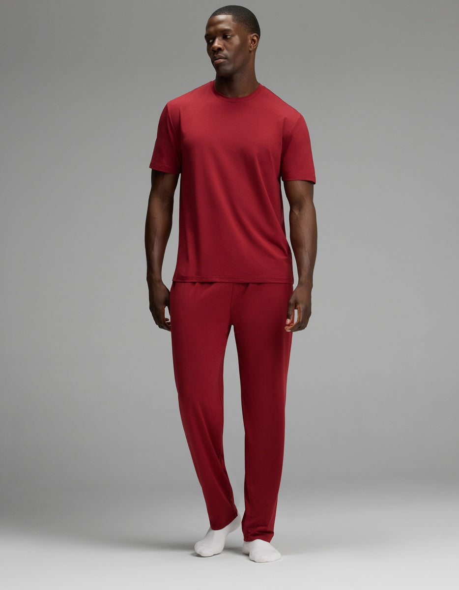 A man wearing a dark red Men’s First Layer Pajama Short Sleeve Tee & Pant Set with white socks.