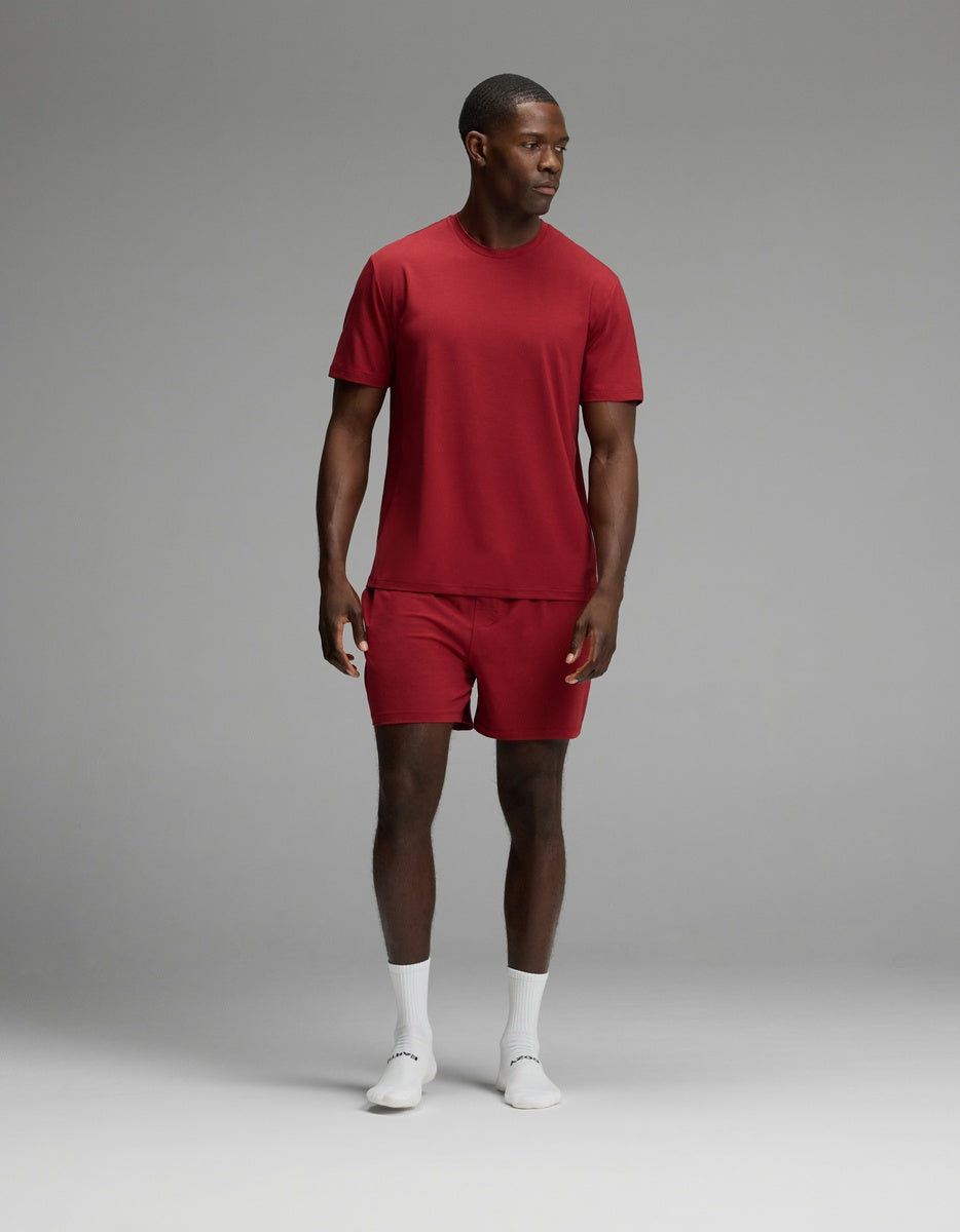 A man wearing a red Men’s First Layer Pajama Short Sleeve Tee & Short Set with white crew socks.