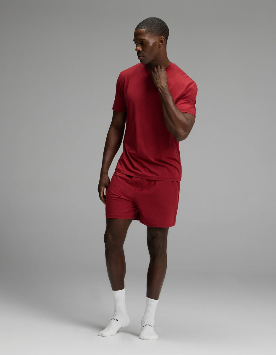A man wearing a red Men’s First Layer Pajama Short Sleeve Tee & Short Set with white socks.
