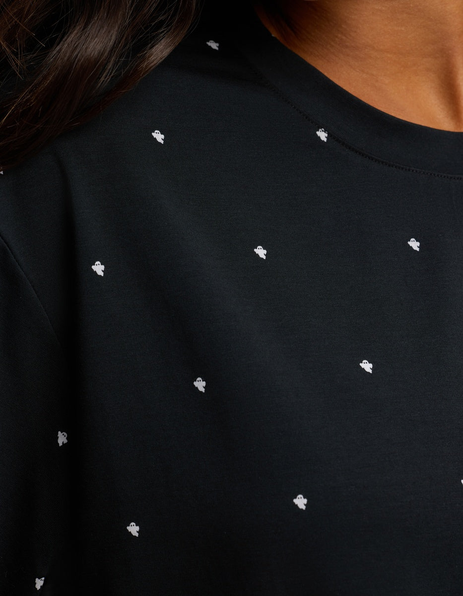 Close-up of a person wearing the Cozy Earth Women’s First Layer Pajama Short Sleeve Tee in black with small white embroidered dot patterns, featuring part of the shoulder, neck, and dark hair.