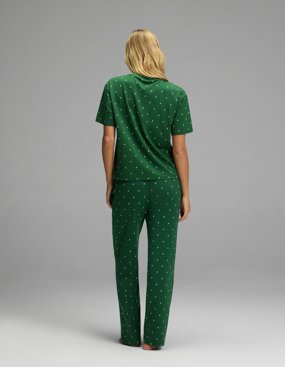 A person seen from behind wears a green Cozy Earth Women’s First Layer Pajama Short Sleeve Tee & Pajama Pant Set featuring a small white tree pattern.