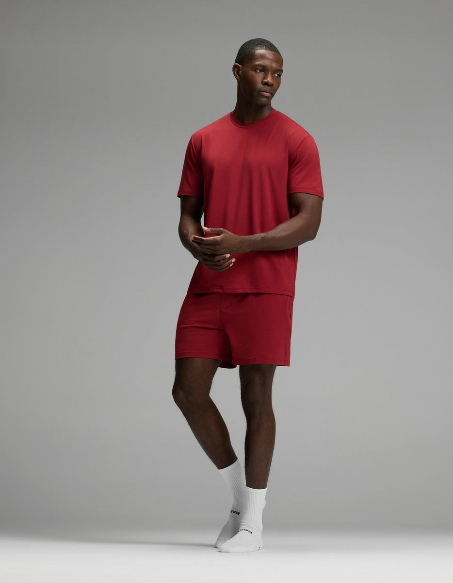 A man wearing a red Cozy Earth Men’s First Layer Pajama Short Sleeve Tee, matching red shorts, and white crew socks.