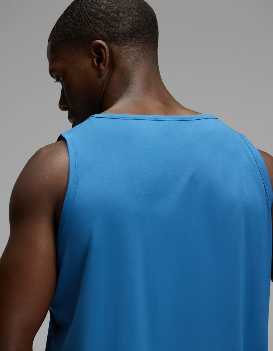 A man wearing the Cozy Earth Men’s First Layer Pajama Tank in blue is seen from behind, looking slightly to the left, against a plain gray background.|Color:Anchor