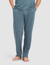 A person stands barefoot with hands in pockets, wearing Cozy Earth Men's First Layer Pajama Pant and a matching top in teal against a plain white background.|Color:Dawn