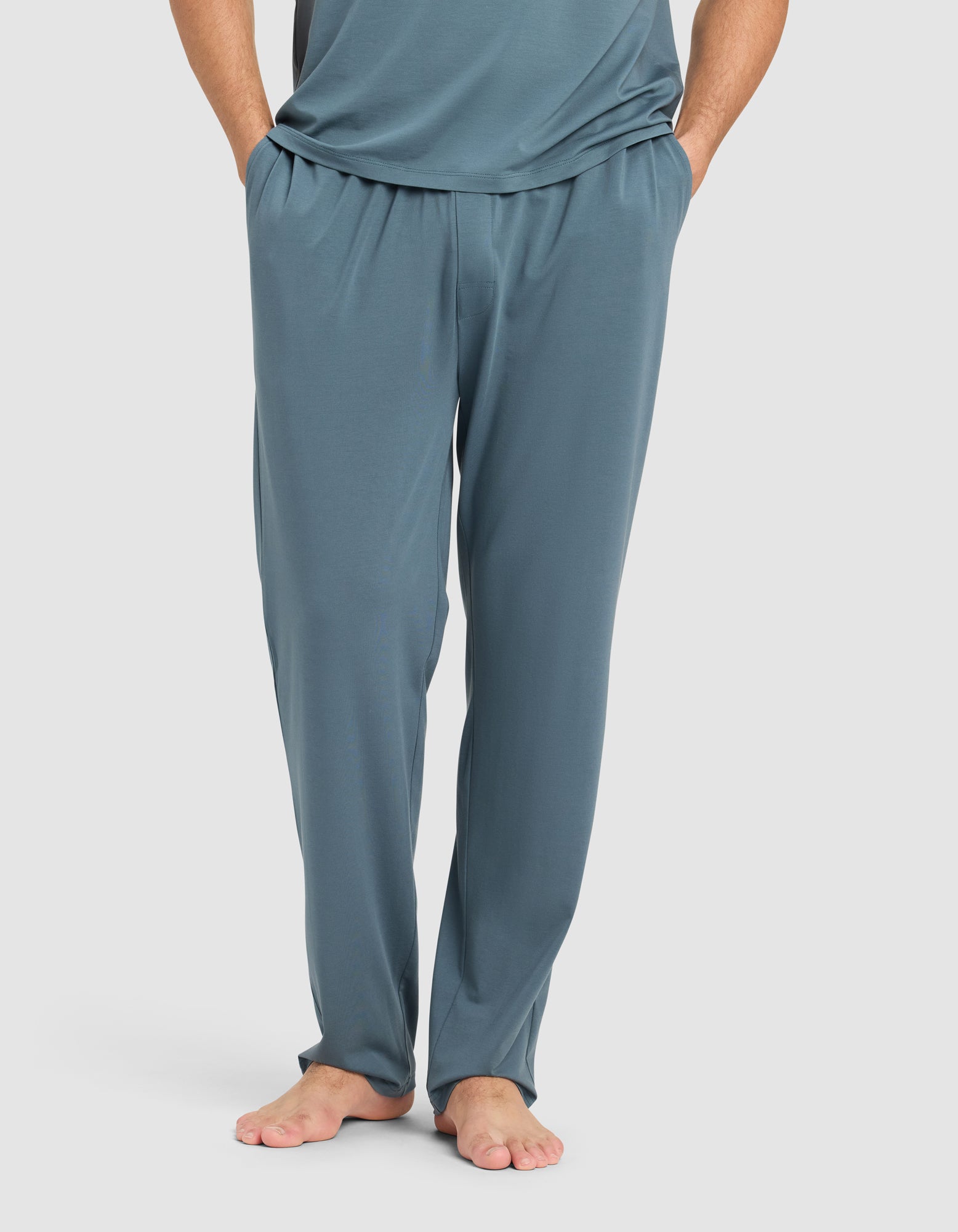 A person stands barefoot with hands in pockets, wearing Cozy Earth Men's First Layer Pajama Pant and a matching top in teal against a plain white background.|Color:Dawn