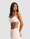 A woman with long dark hair stands in profile against a light gray background, wearing the Cozy Earth Women's First Layer Pajama Soft Bra and matching shorts. She looks to the side with her hands behind her back.|Color:Ballet