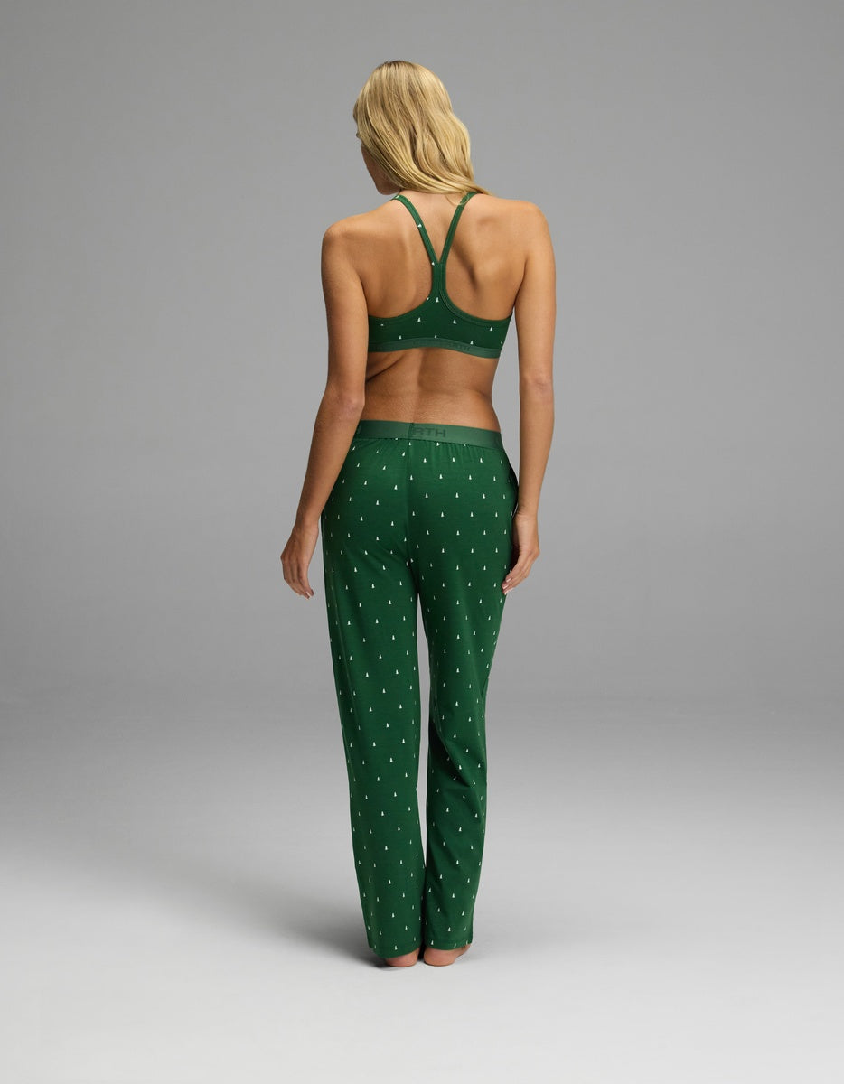 Back view of a woman wearing a dark green Women’s First Layer Pajama Soft Bra & Pajama Pant Set featuring a racerback bralette and pants with a small white tree pattern.