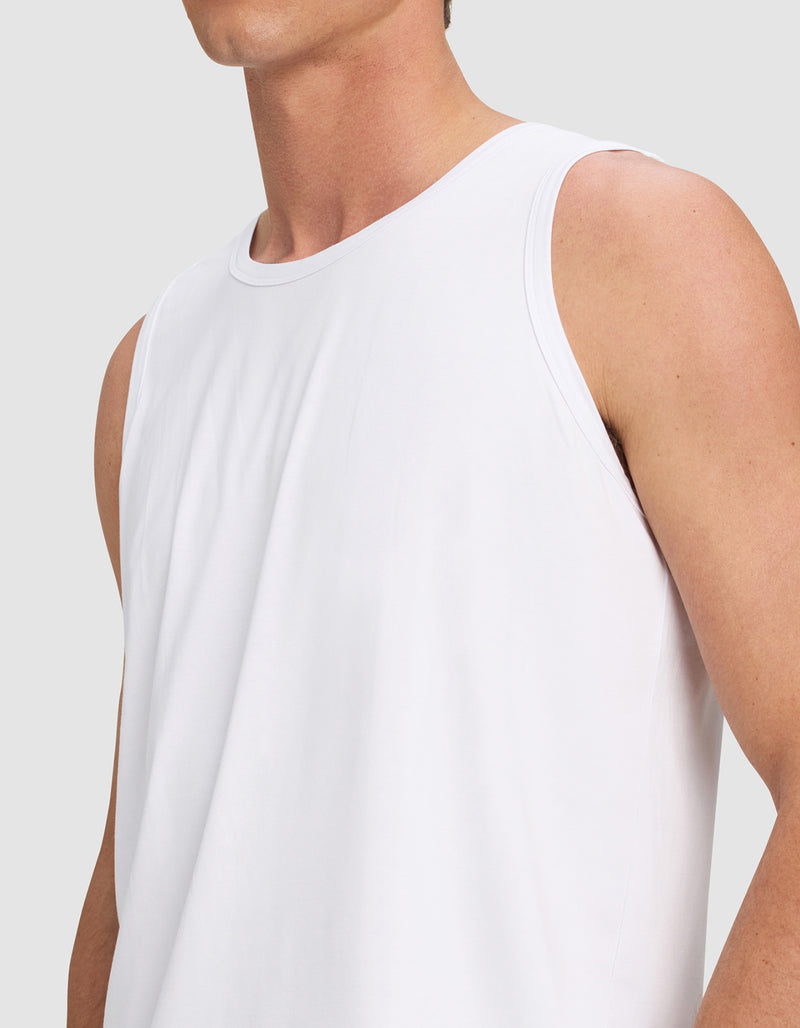 A person is shown from shoulders to waist wearing the Cozy Earth Men's First Layer Pajama Tank in white against a plain light gray background, with their face partially out of frame.