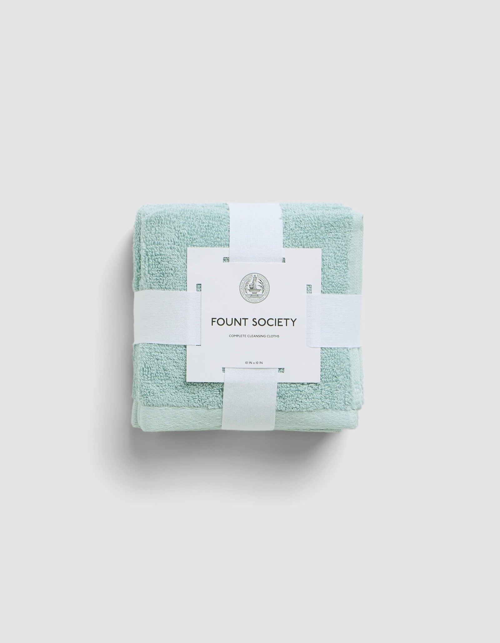 A neatly folded light green Complete Cleansing Cloth by Cozy Earth, secured with white bands and branded tag, rests against a light gray background.