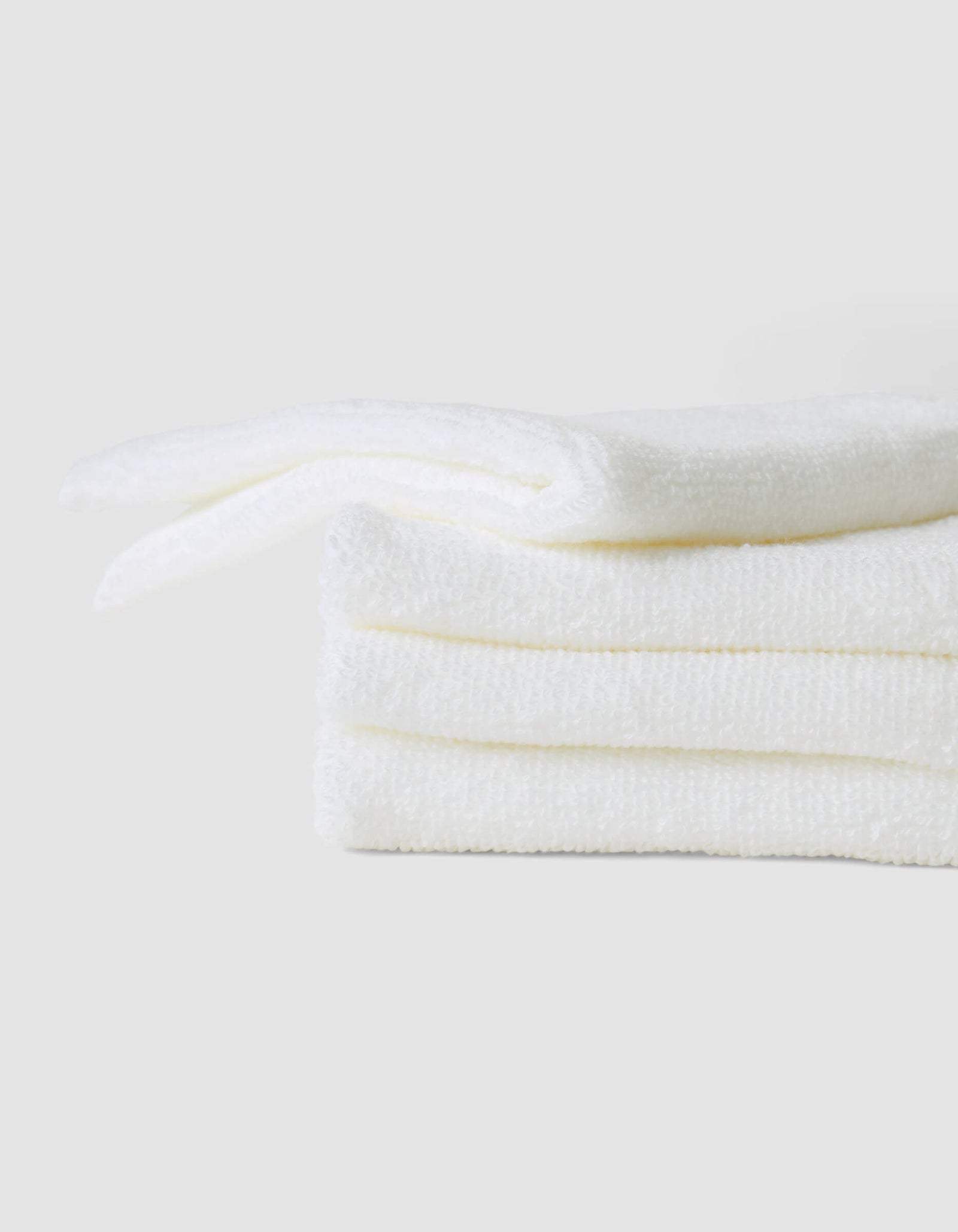 A stack of three neatly folded white Cozy Earth Complete Cleansing Cloths is displayed against a plain light gray background.