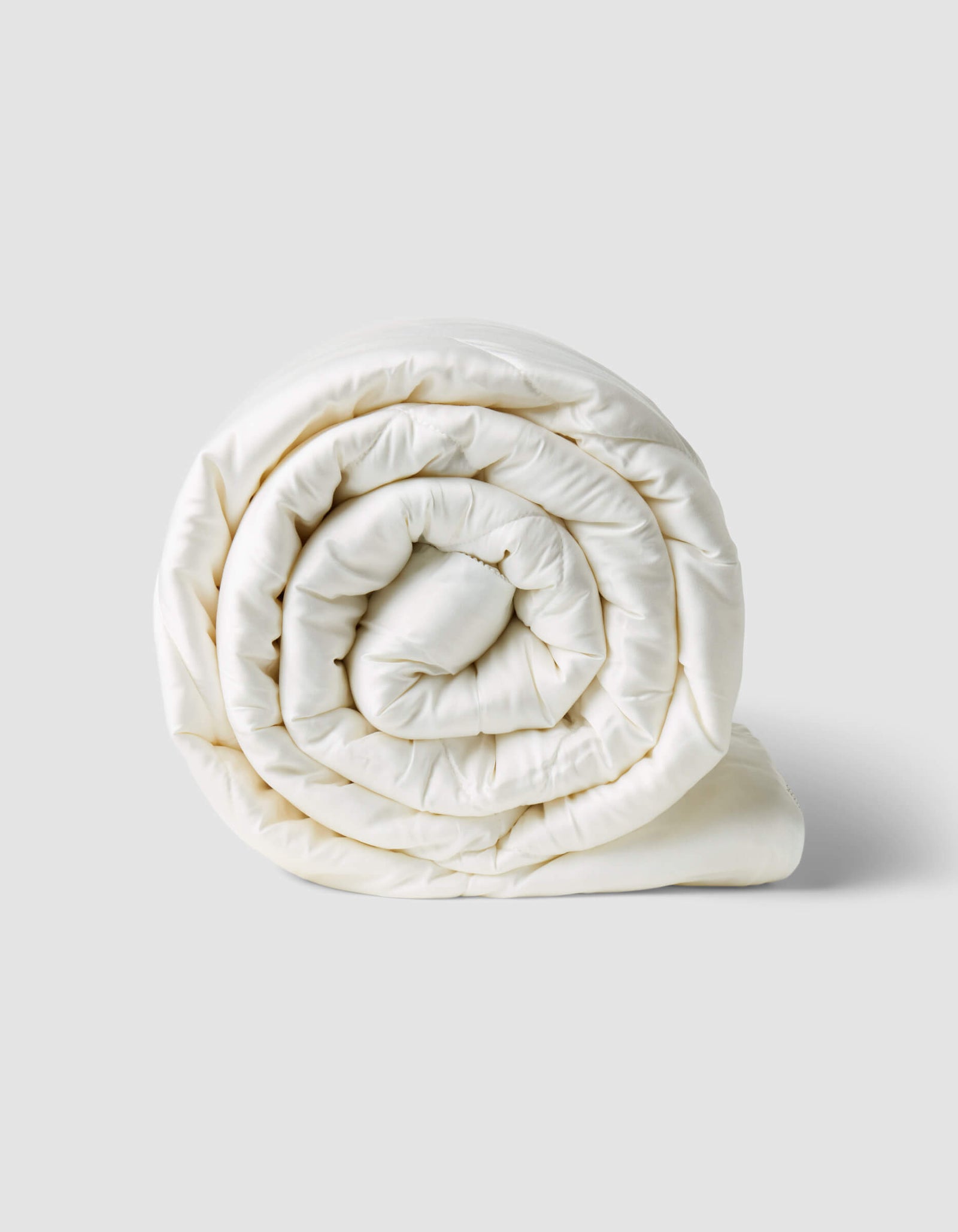 The Cozy Earth Bamboo Viscose Comforter, in crisp white, is shown neatly rolled on a plain light gray background.