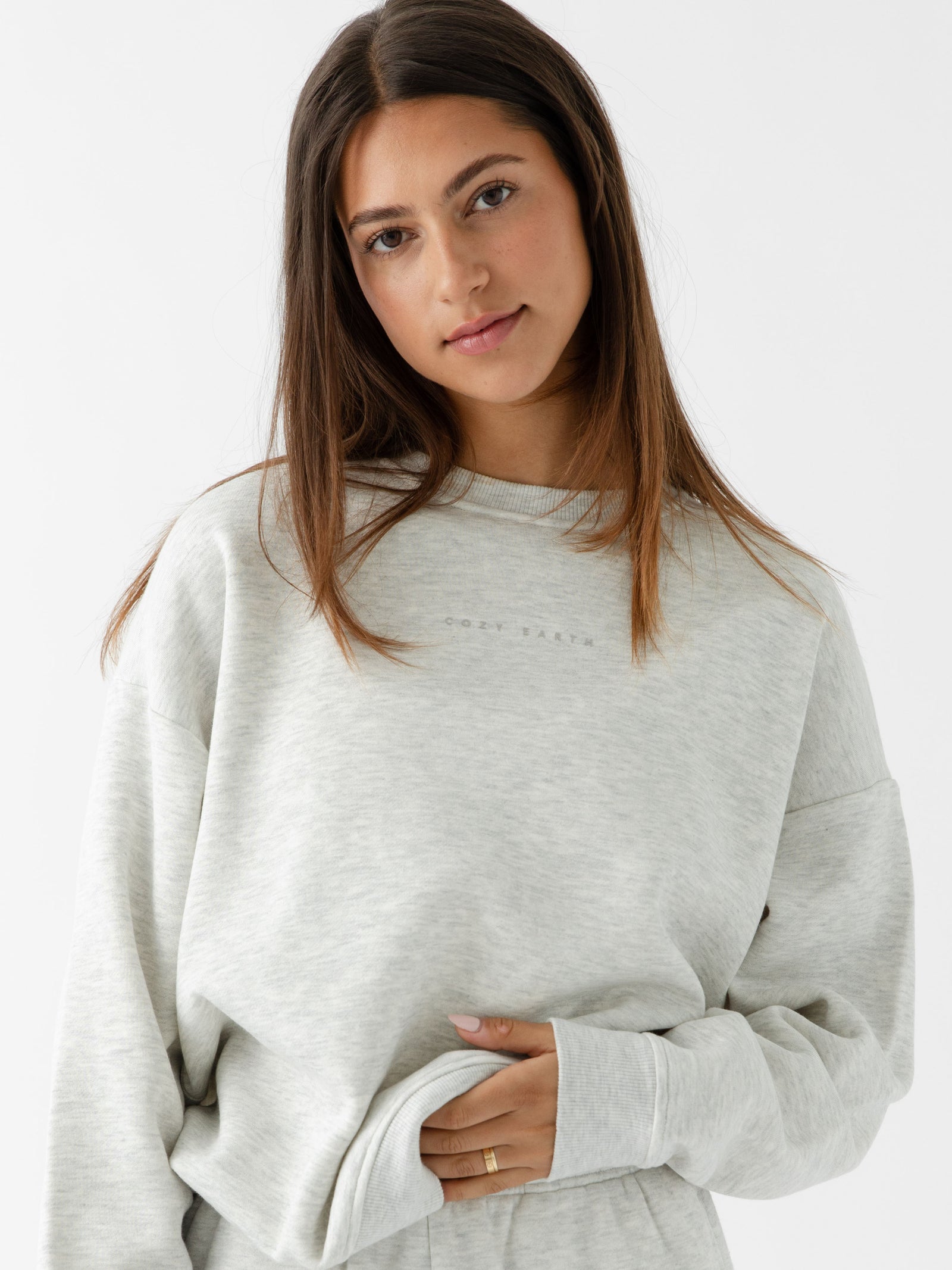 Heather Grey CityScape Pullover Crew. The Pullover is being worn by a female model. Accompanying city scape clothing is being worn to complete the look of the outfit. The photo was taken with a white background. 