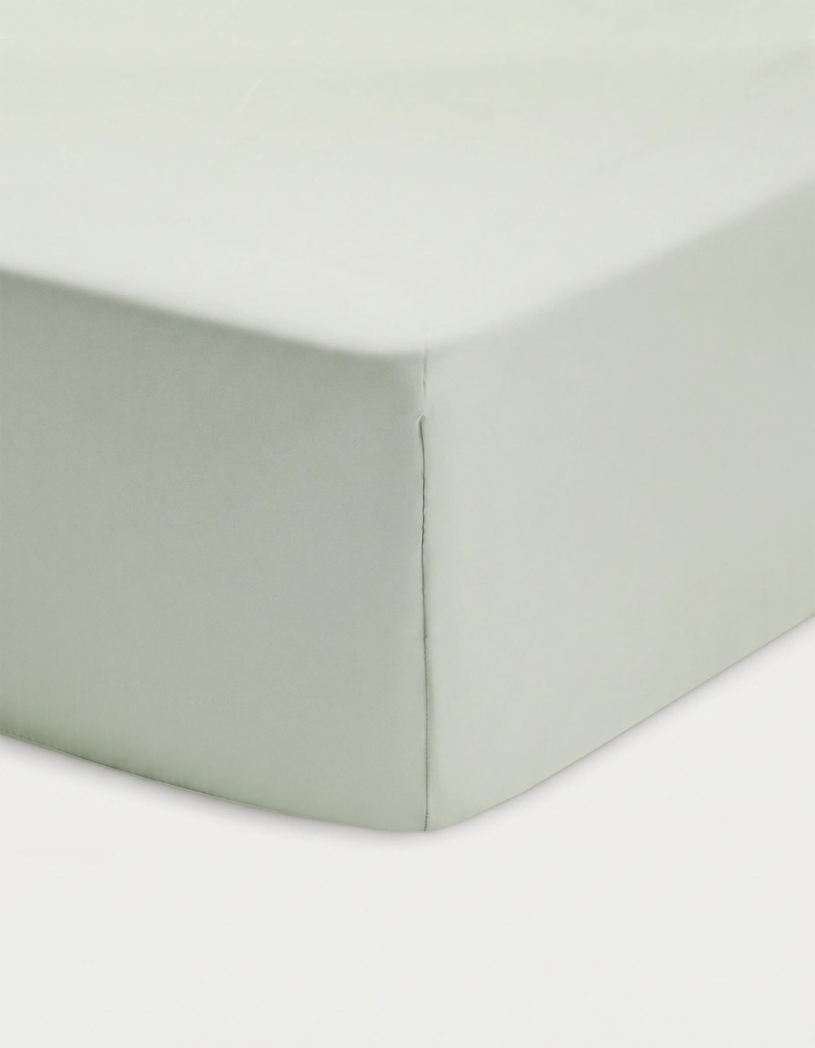 Close-up of a corner of a bed showcasing the Cozy Earth Bamboo Fitted Sheet in light green, neatly covering the mattress against a white background.