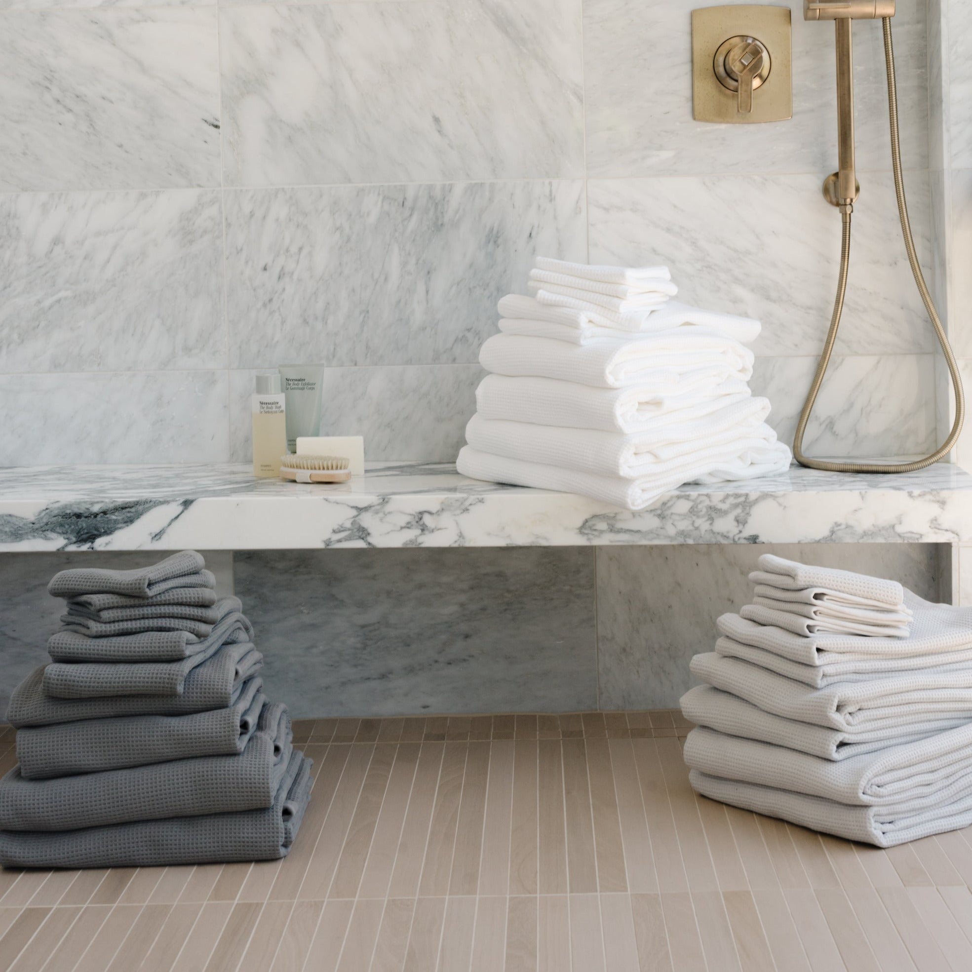 Complete Waffle Bath Bundle in the colors Charcoal, White, and Light Grey. Photo of Charcoal, White, and Light Grey Complete Waffle Bath Bundle taken while towels rest on bathroom floor