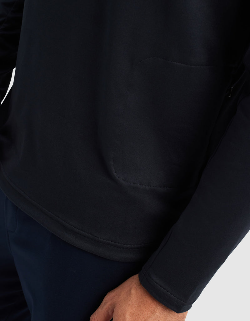 A close-up of a person wearing the Cozy Earth Men's Lightweight Performance Hoodie in black, with dark pants; their right hand rests at their side, and the hoodie's pocket seam is visible.