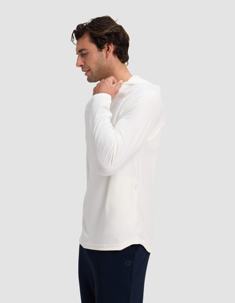 A man wearing the Cozy Earth Men's Lightweight Performance Hoodie in white and dark pants faces left, holding the hood with one hand against a plain light gray background.