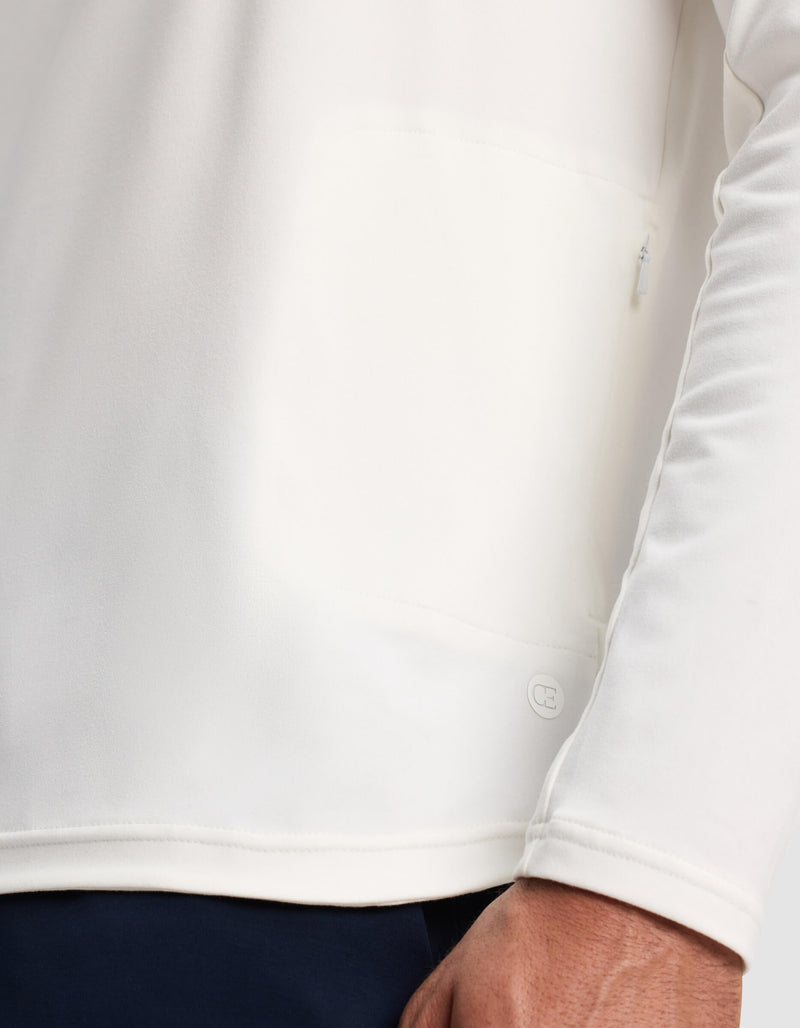 A close-up of a person wearing the Cozy Earth Men's Lightweight Performance Hoodie in white, highlighting the lower hem, a small logo detail, and part of the person's hand.