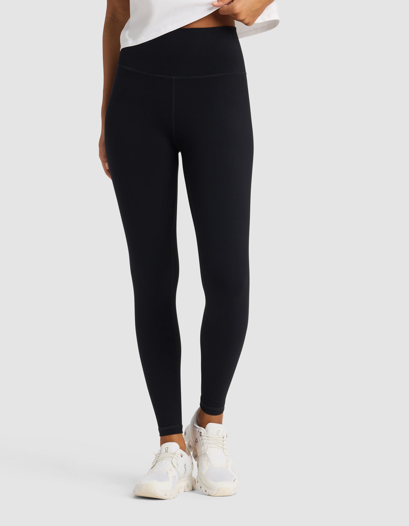 A model wears Cozy Earth Women's Liv Legging in black with a white top and sneakers, standing against a light gray background. The image is cropped to display only the lower half of the body.
