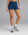 Waist-down view of a woman wearing dark blue Women’s Liv Biker Short 4″, white crew socks, and gray sneakers.|Color:Obsidian