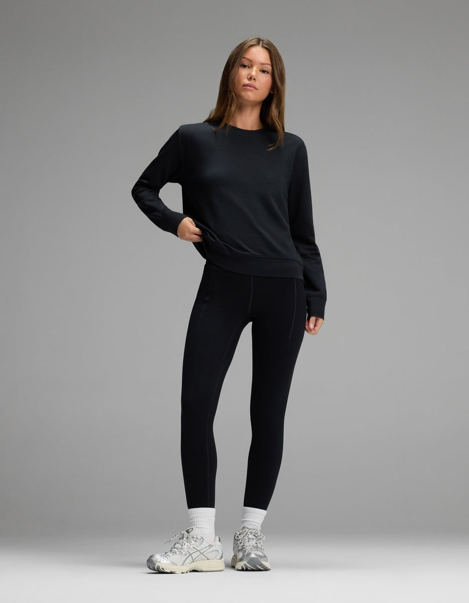 A person wearing a black long-sleeve shirt, black Women’s Liv Leggings with Pockets, white socks, and athletic shoes.