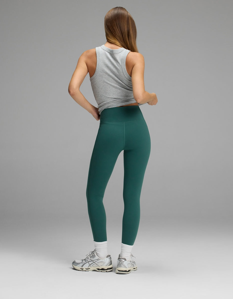 A person viewed from behind wearing a gray tank top and forest green Women’s Liv Leggings with Pockets.|Color:Uniform