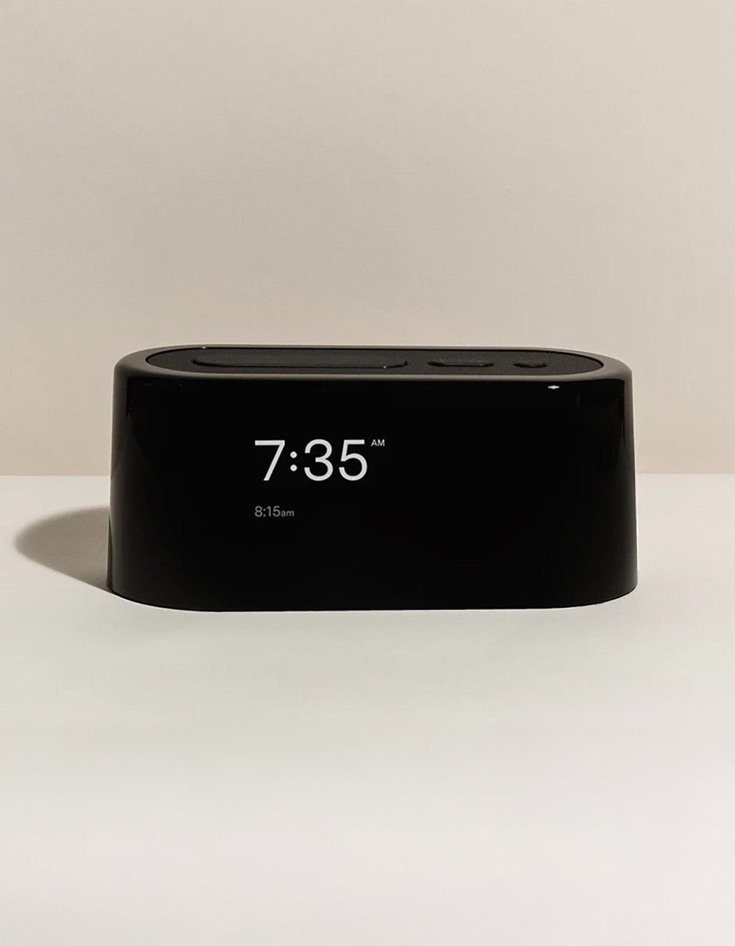 The Cozy Earth Bamboo Sheet Set x Loftie Clock is shown on a white surface with a beige background, its screen displaying 7:35 AM and an alarm set for 8:15 AM.