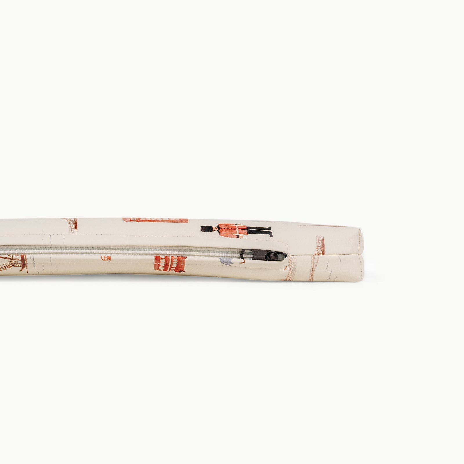 A close-up side view of two cream-colored Gathre Wholesale Padded Changing Mats stacked, featuring a print of red British guard soldiers and a mailbox. The top mat shows a visible black zipper.