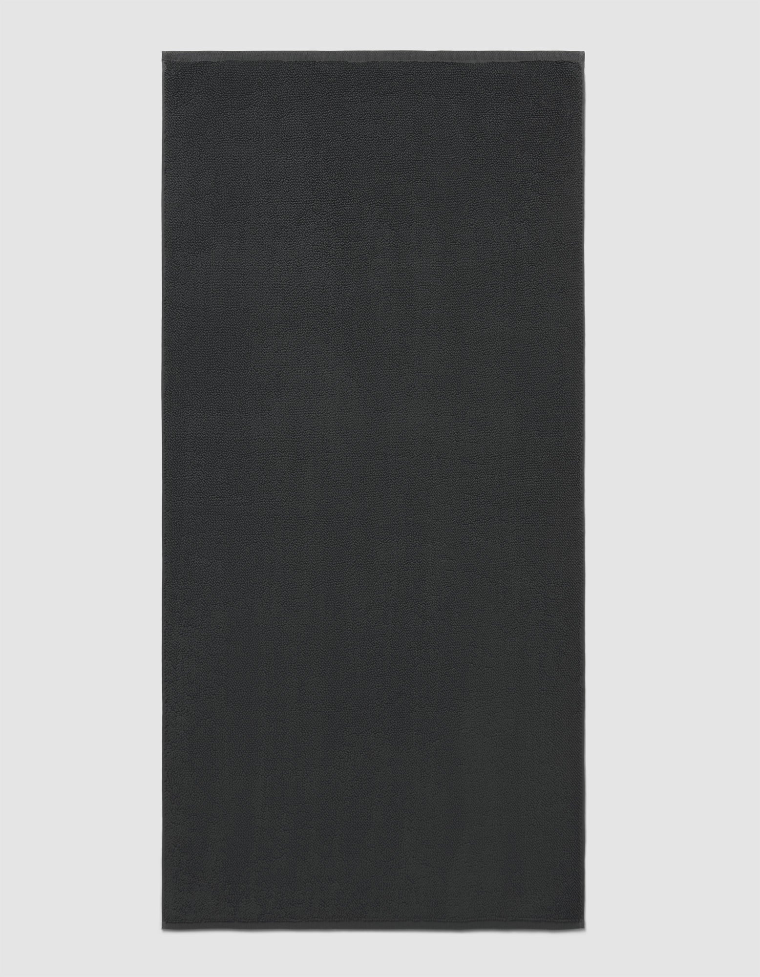 The Cozy Earth Loop Terry Bath Mat is rectangular and solid dark gray with a soft, uniform texture, shown against a plain light background.|Color:Graphite