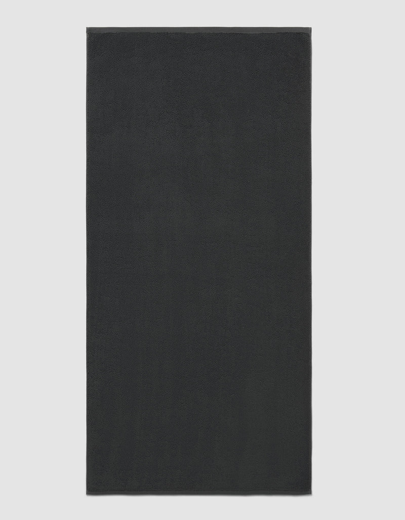 The Cozy Earth Loop Terry Bath Mat is rectangular and solid dark gray with a soft, uniform texture, shown against a plain light background.