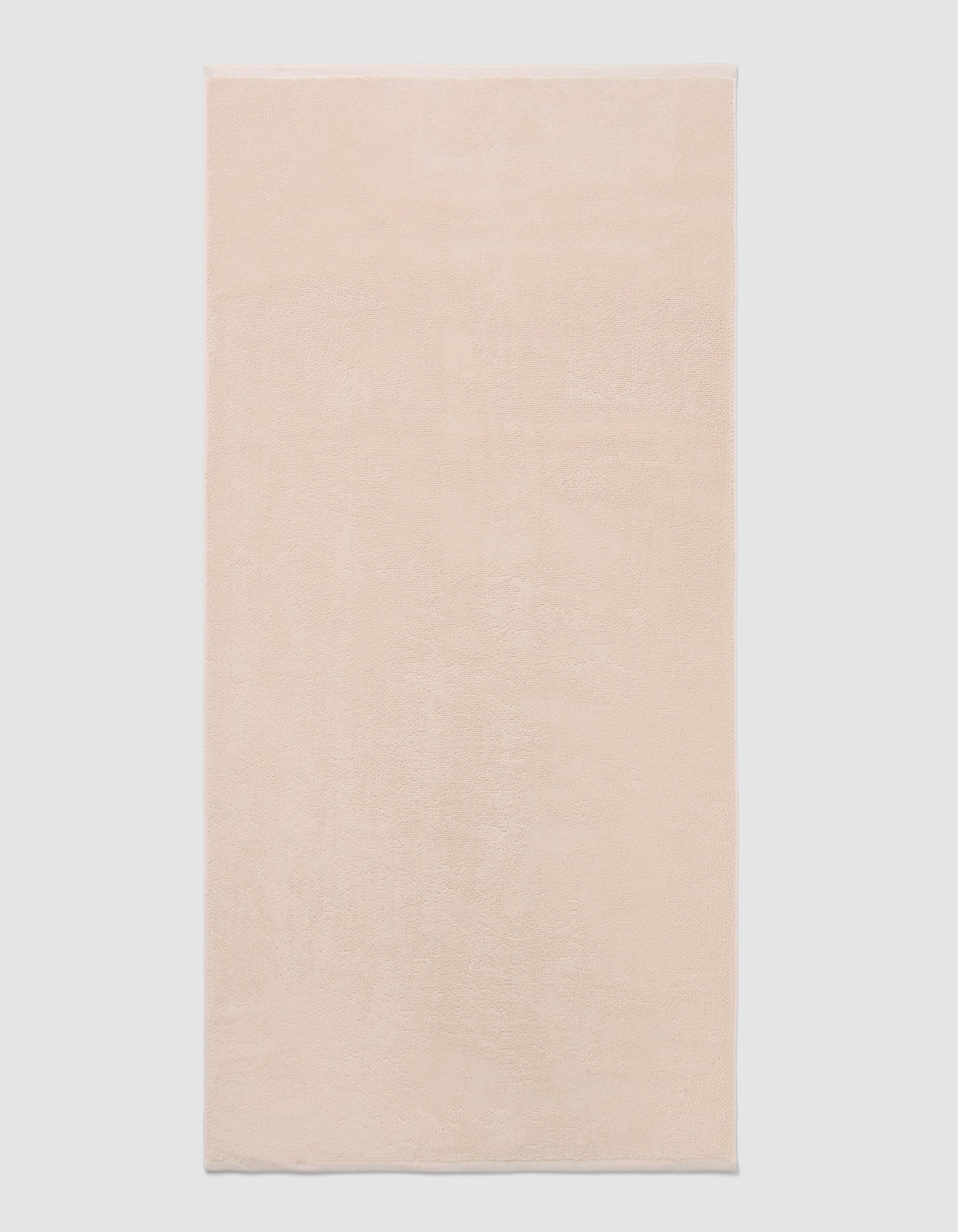 The Cozy Earth Loop Terry Bath Mat, a rectangular bath mat in light beige with a soft, plush texture, is displayed against a plain white background.|Color:Petal