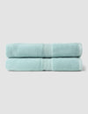 Two Luxe Bath Sheets by Cozy Earth, neatly folded and stacked, feature a light blue color against a plain, light gray background.|Color:Tide