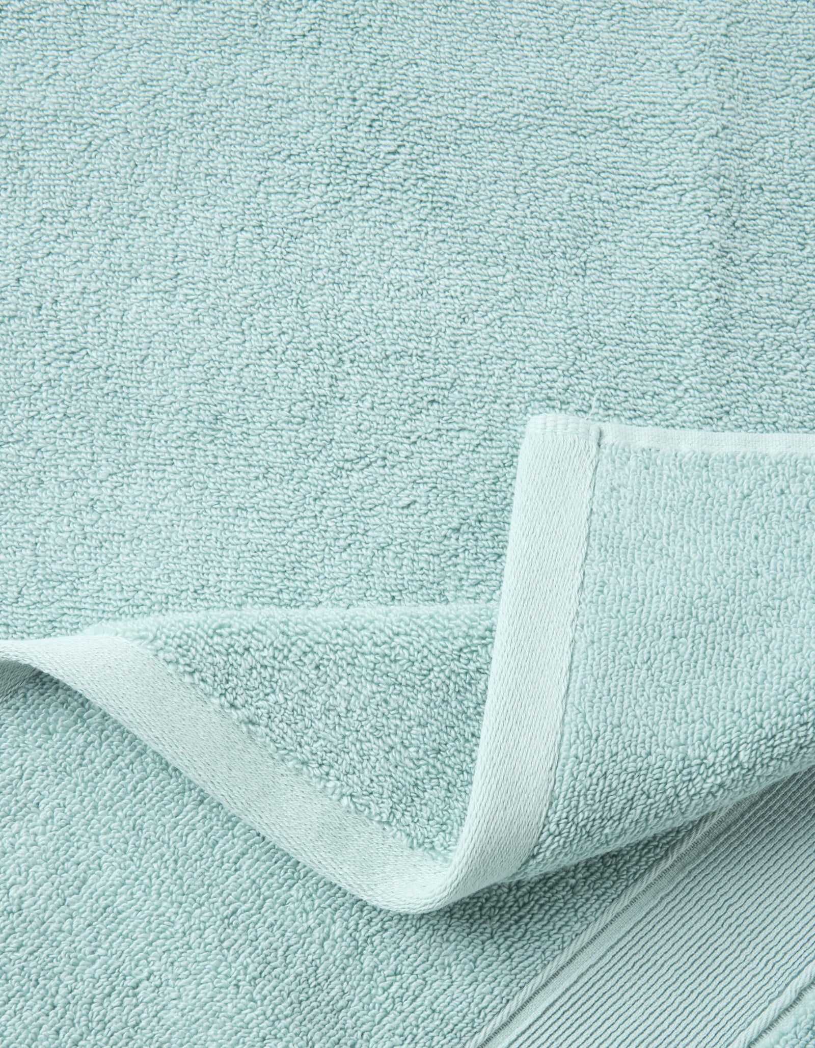 A close-up of the Luxe Bath Sheets by Cozy Earth in light blue highlights their textured, soft surface and neatly folded edge, showcasing the towel’s plush thickness and detailed hem.