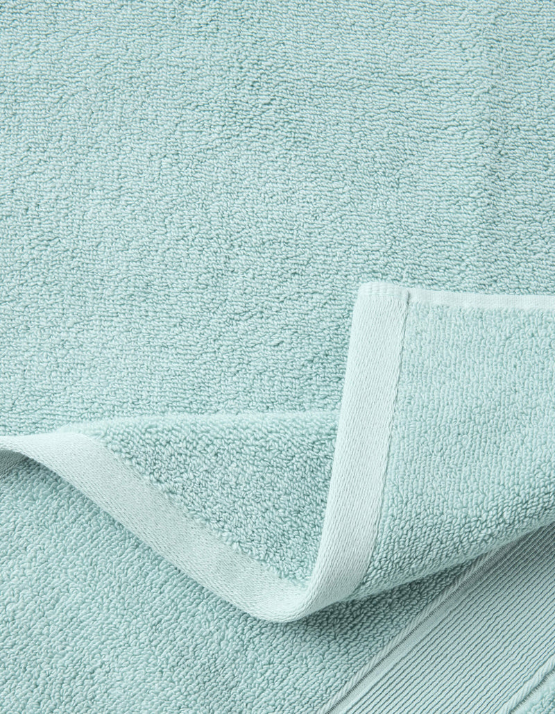 A close-up of the Luxe Bath Sheets by Cozy Earth in light blue highlights their textured, soft surface and neatly folded edge, showcasing the towel’s plush thickness and detailed hem.