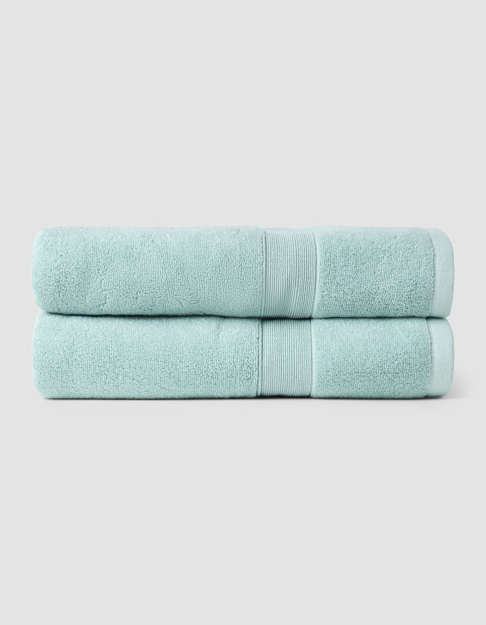 Two Luxe Bath Towels by Cozy Earth, neatly folded and stacked, are displayed against a plain light gray background.