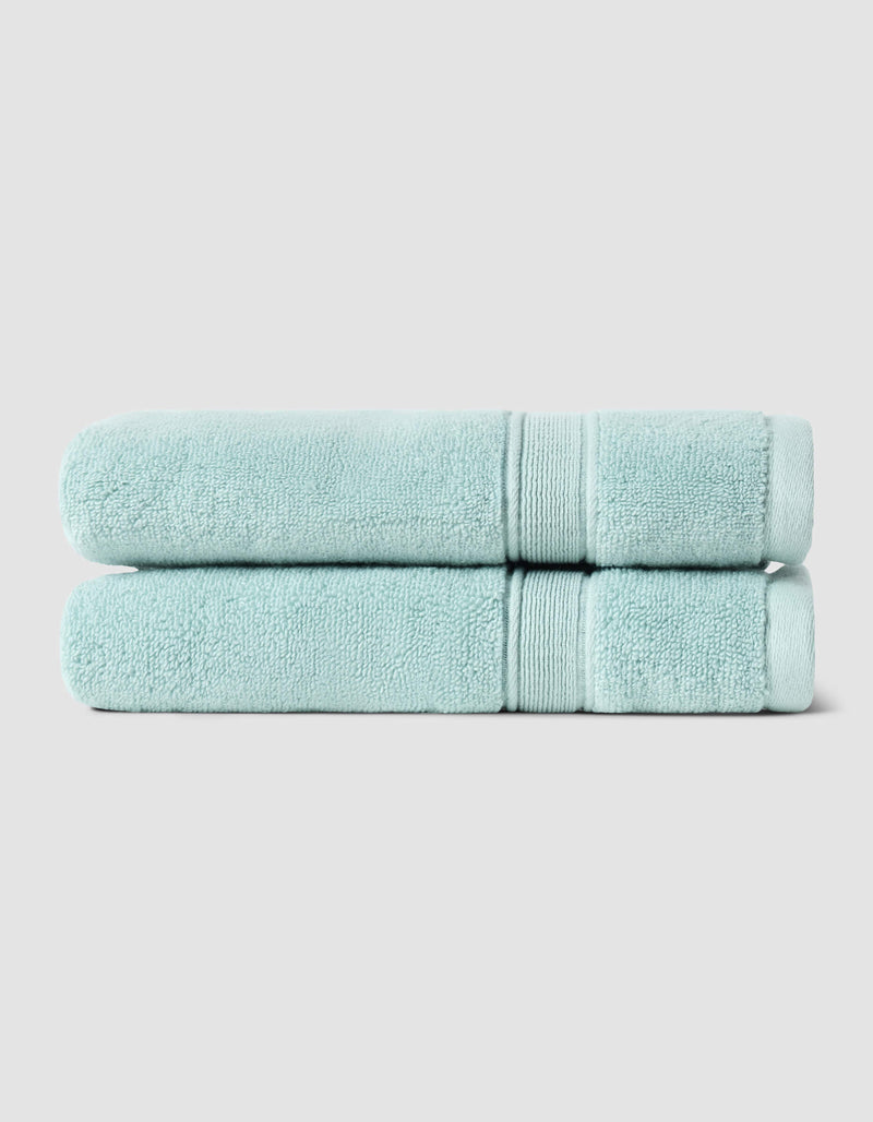 Two Luxe Bath Towels by Cozy Earth, neatly folded and stacked, are displayed against a plain light gray background.