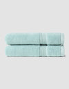 Two neatly folded Luxe Hand Towels by Cozy Earth, in light blue, are stacked atop each other against a plain light gray background.|Color:Tide