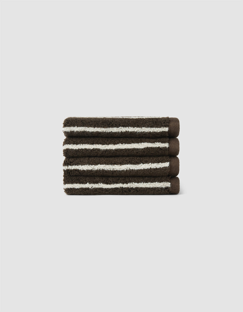 The Cozy Earth Striped Luxe Bath Towel Set features three neatly folded dark brown towels with white stripes, stacked on a light gray background.