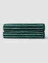 Two Luxe Bath Sheets by Cozy Earth in dark green with thin white stripes are neatly folded and stacked against a plain light gray background.|Color:Uniform with Seashell Stripe
