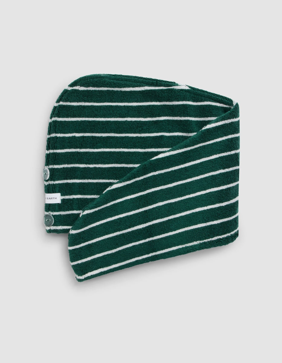 The Luxe Hair Towel by Cozy Earth features dark green and white stripes, two snap buttons, and a small white tag on the edge, folded to reveal both sides.|Color:Uniform with Seashell Stripe