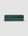 Two Luxe Hand Towels by Cozy Earth, dark green with white horizontal stripes, are neatly rolled and stacked against a plain light gray background.|Color:Uniform with Seashell Stripe