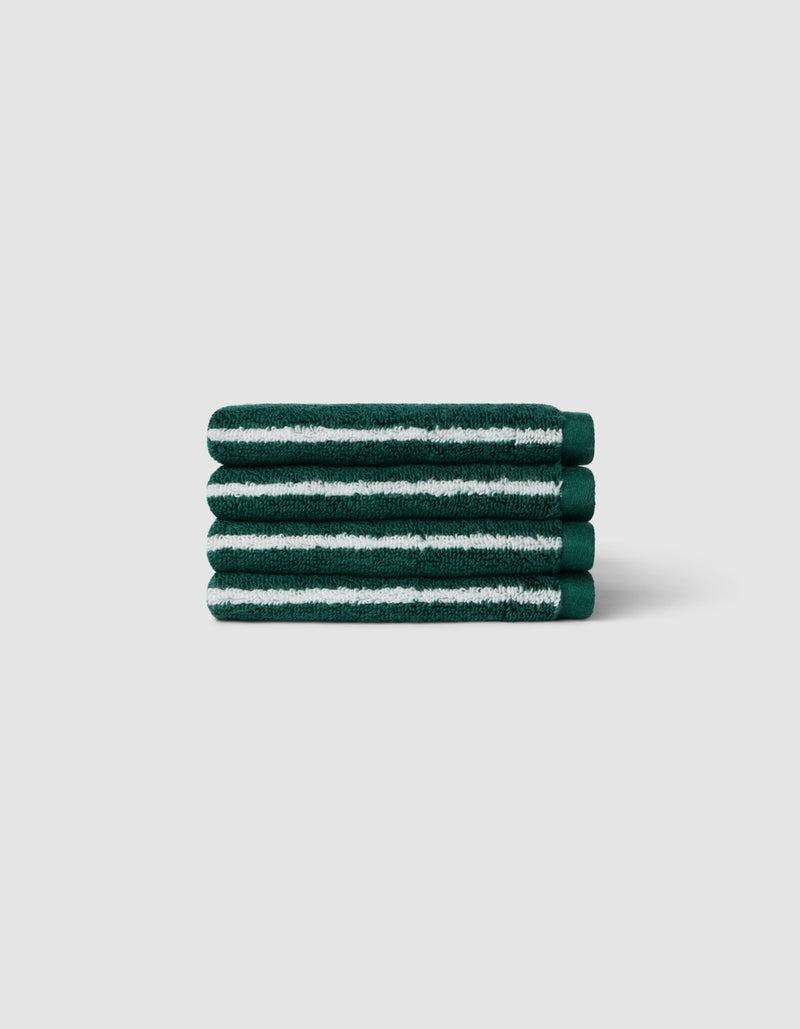 A stack of four Luxe Washcloths by Cozy Earth in dark green with white stripes, displayed against a light gray background.