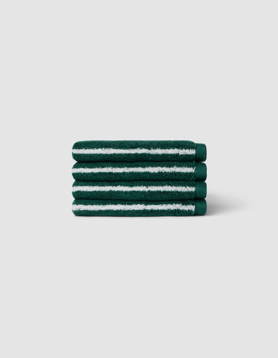 A stack of four Luxe Washcloths by Cozy Earth in dark green with white stripes, displayed against a light gray background.|Color:Uniform with Seashell Stripe