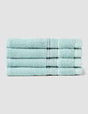 Four neatly folded Luxe Washcloths by Cozy Earth, in light blue, stacked on top of each other against a plain light gray background.|Color:Tide