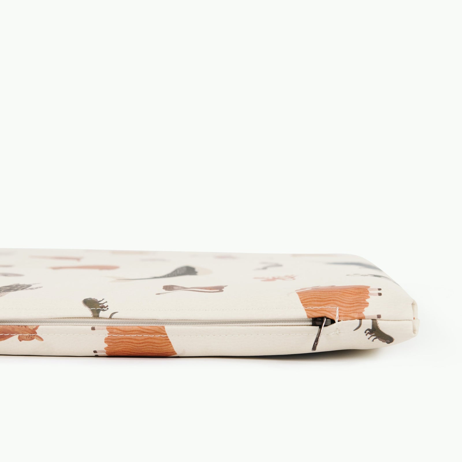 A close-up of the Gathre Wholesale Padded Changing Mat shows playful animal and object illustrations in orange, brown, and green on a cream background. The partially visible zipper is on the right.