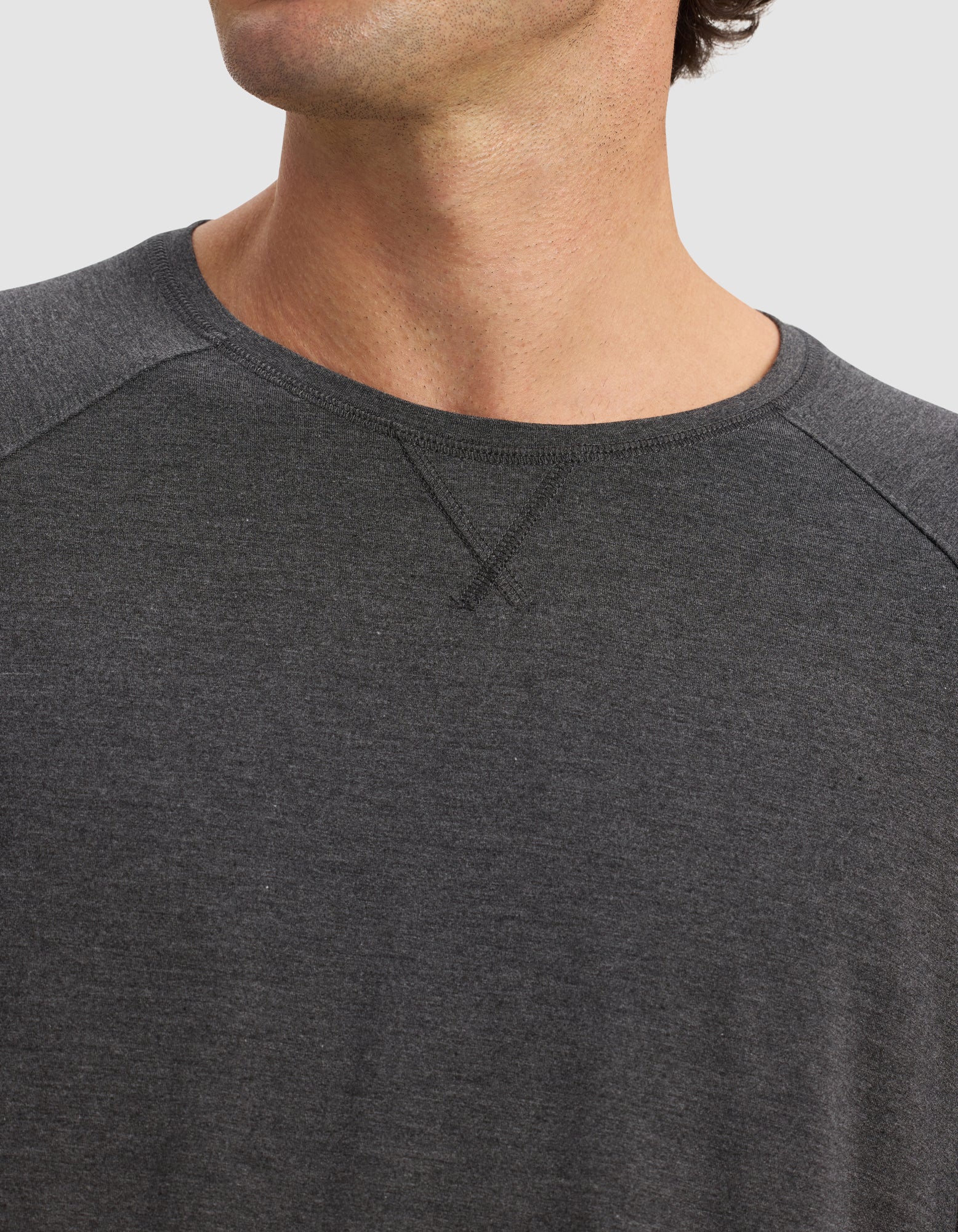 Close-up of a person wearing the Cozy Earth Men's Bamboo Stretch-Knit Long Sleeve in dark gray with raglan sleeves. The face is partially hidden, and the background is plain white.|Color:Charcoal